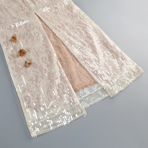 Détail de la robe de soirée en dentelle champagne avec sequins et fleurs en relief