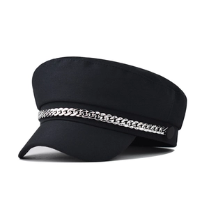 Detailed view of silver chain ornament on a black cotton baker boy cap with flat top