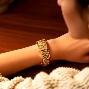 Detail of 18k gold plated geometric bracelet with green marquise stones and belt buckle clasp