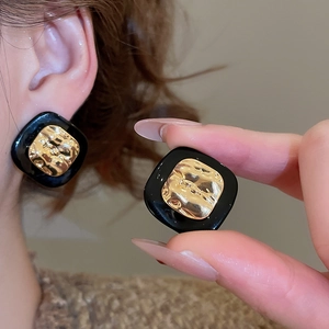 Detail of square black stud earring featuring hammered gold texture and vintage design