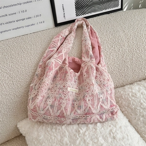 Close-up of pink lace floral embroidery and delicate texture on a canvas shoulder bag