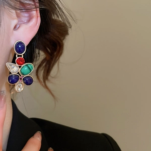 Detail of vintage palace style earrings with colorful gemstones and crystals on a model