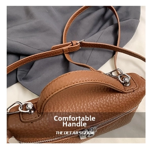 Close-up of caramel pebble leather handbag showing top handle and silver hardware