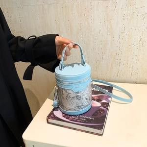 Chic light blue cylindrical bucket bag with intricate lace embroidery and PU leather details