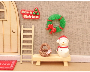 Detailed macro view of miniature Christmas dollhouse set with snowman and wooden furniture