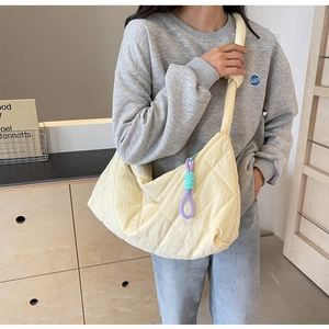 Detail of light yellow quilted tote bag with knot shoulder strap and colorful rope charm