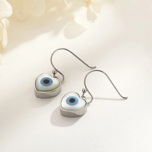 Macro detail of silver heart-shaped Evil Eye earrings with white shell inlay