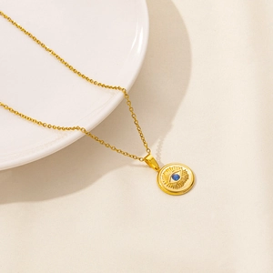 Detailed close-up of golden evil eye coin pendant necklace with a blue gemstone center
