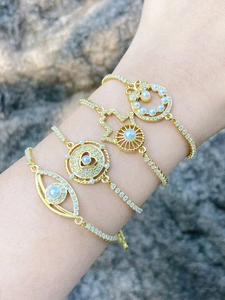 Pulseras doradas apiladas con perlas y mano de Fátima en la muñeca de una modelo