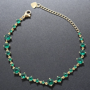 Detail view of a gold adjustable bracelet featuring multi-sized green round-cut gemstones