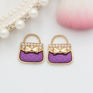 Detail of purple handbag charms with gold lattice, bow accent and small pearls