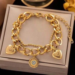 Détail du bracelet en acier titane doré avec breloques œil bleu et cœurs gravés
