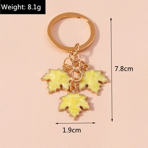 Macro view showing dimensions and weight of yellow maple leaf keychain with enamel finish