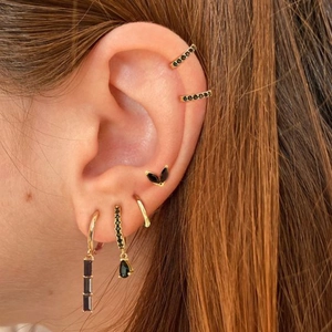 Close-up of gold-plated earrings and ear cuffs featuring black cubic zirconia accents