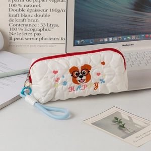 Detail of white quilted pencil case featuring cute dog embroidery and a red zipper