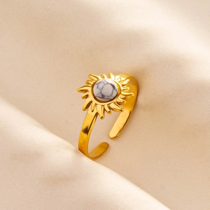 Detail of adjustable gold ring with sunflower design and white marble texture stone