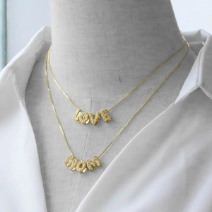 Double-layered gold letter pendant necklace with LOVE and MOM charms on a model