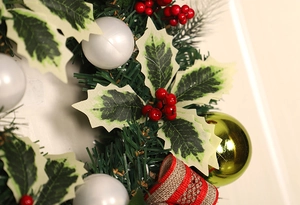 Close-up of Christmas wreath featuring red and white berries with rustic striped ribbon