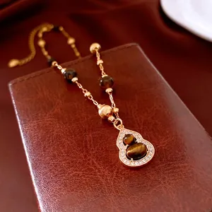 Tiger eye bead necklace with gold plated gourd pendant and crystals on leather display