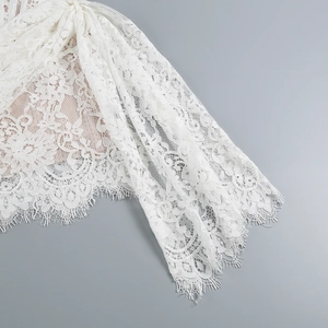 Detailed macro view of white eyelash lace fabric with intricate floral mesh textures