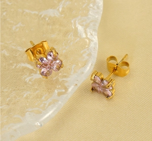 Détail de boucles d'oreilles trèfle avec zircons cœurs roses sur base en acier doré