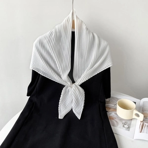 Detail of white pleated shawl scarf with fine vertical texture draped on a black dress