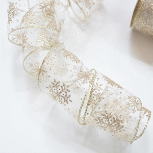 Detail of white semi-transparent chiffon ribbon with glittering gold snowflake print