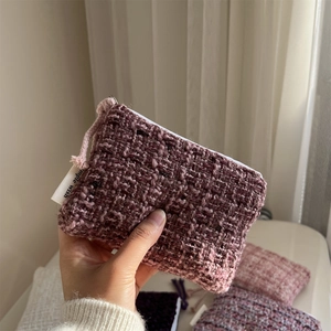 Close-up of purple tweed zipper pouch showing woven fabric texture and logo tag