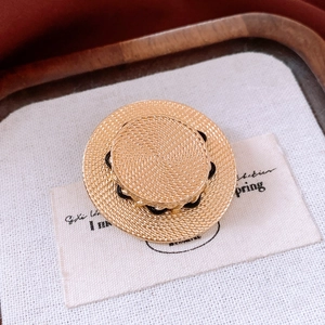 Gros plan détaillé d'une broche chapeau de paille vintage à texture tissée dorée
