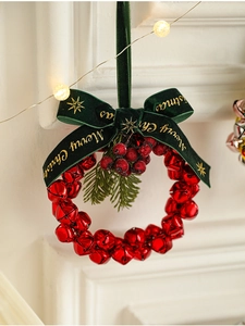Detail of red metal Christmas bell wreath with velvet bow and berries on pine needles