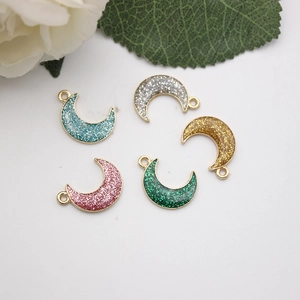 Detailed view of moon-shaped charms with glitter resin filling and metal loops for DIY jewelry