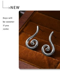 Detail of silver conch-shaped spiral earrings inside a vintage velvet jewelry box