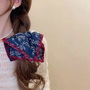 Detail of blue floral knot headband with red contrast edge stitching on braided hair