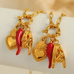 Golden multi-pendant necklace with red chili, sacred heart, and hand charm on white