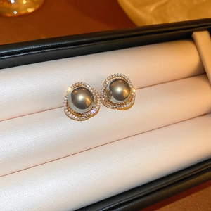 Gros plan de boucles d'oreilles en perles grises avec cadre doré et cristaux fins