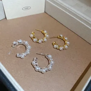 Gold and silver plated C-shaped hoop earrings with pearls and zircons on a jewelry tray
