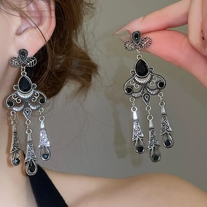Macro detail of vintage silver tassel earrings featuring black gemstone inlays and leaves
