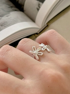 Close-up of 925 sterling silver daisy ring on finger with soft lighting and book background