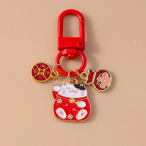 Lucky cat keychain with red fortune bag and copper coin charm on beige background