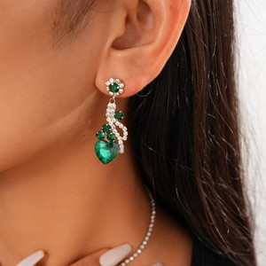 Detail of luxury flower and heart drop earrings with green crystal and diamonds