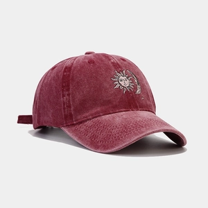 Detail of vintage washed burgundy baseball cap with sun and moon embroidery texture