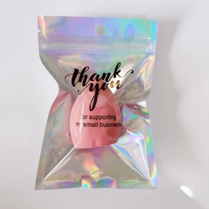 Close-up of holographic packaging with a pink teardrop makeup sponge and thank you text