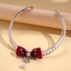 Macro detail of red velvet bow necklace with snowflake pendant and faux pearls
