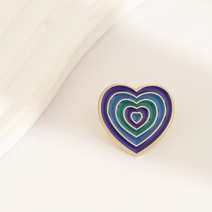 Detailed view of concentric teal and blue heart enamel badge with gold metallic trim