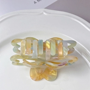 Detail of a pearlized heart-shaped hair claw clip with rhinestones on a ceramic dish
