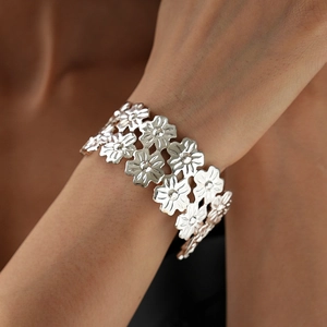 Detailed close-up showing the intricate floral pattern and metallic finish on the open cuff bangle