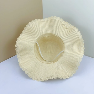 Close-up of a wide-brim straw hat with wavy edges and an adjustable elastic chin strap