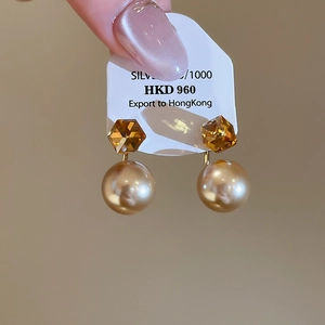 Macro view of 18K gold plated S925 silver earrings with amber crystal and champagne pearl