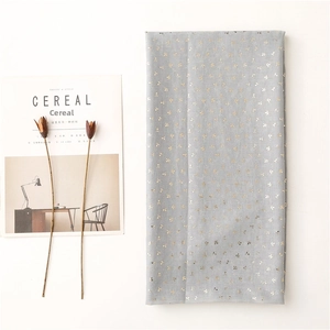 Detailed view of grey cotton-linen fabric with gold leaf pattern and wavy edges