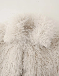 Gros plan détaillé sur la texture pelucheuse en fausse fourrure crème du col et de l'épaule